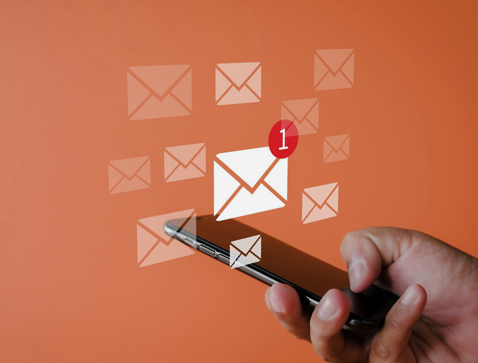 Hand holding a smartphone with an email notification. Floating email icons on orange background.