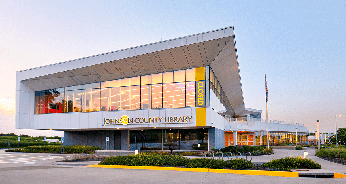 Johnston County Library building with large windows and yellow accents under a bright sky.