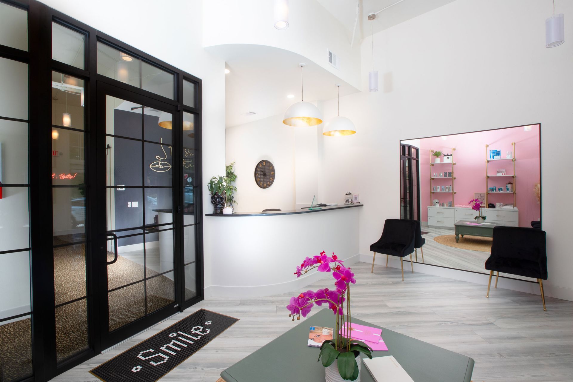 Modern bright dental office lobby with black-framed glass doors, black chairs, and pink flowers on a table