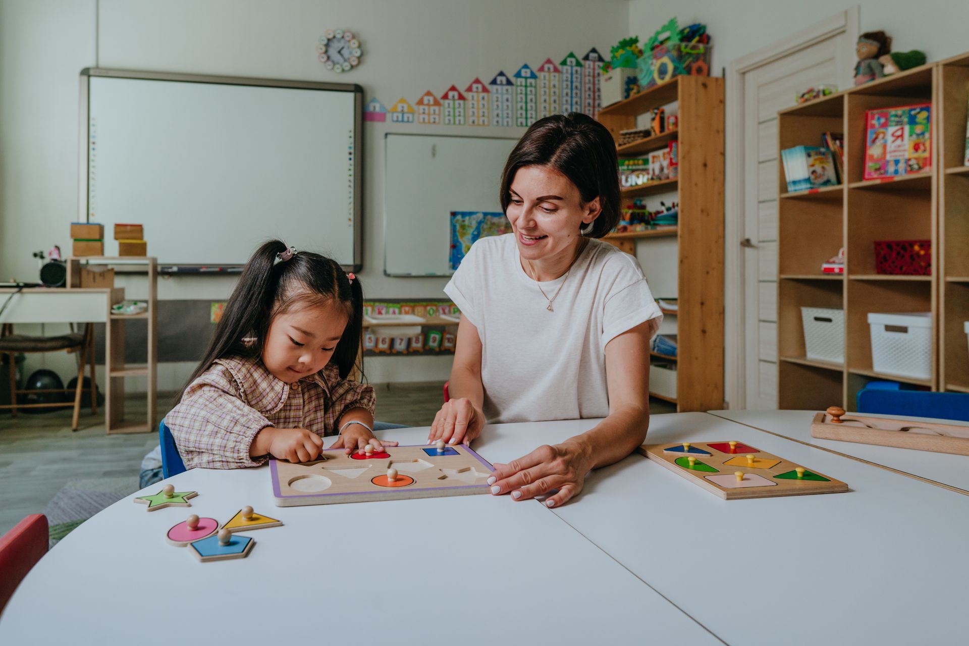 A woman and child playing with puzzles in a classroom, part of the toddler program activities. A woman and child playing with puzzles in a classroom, part of the toddler program activities.