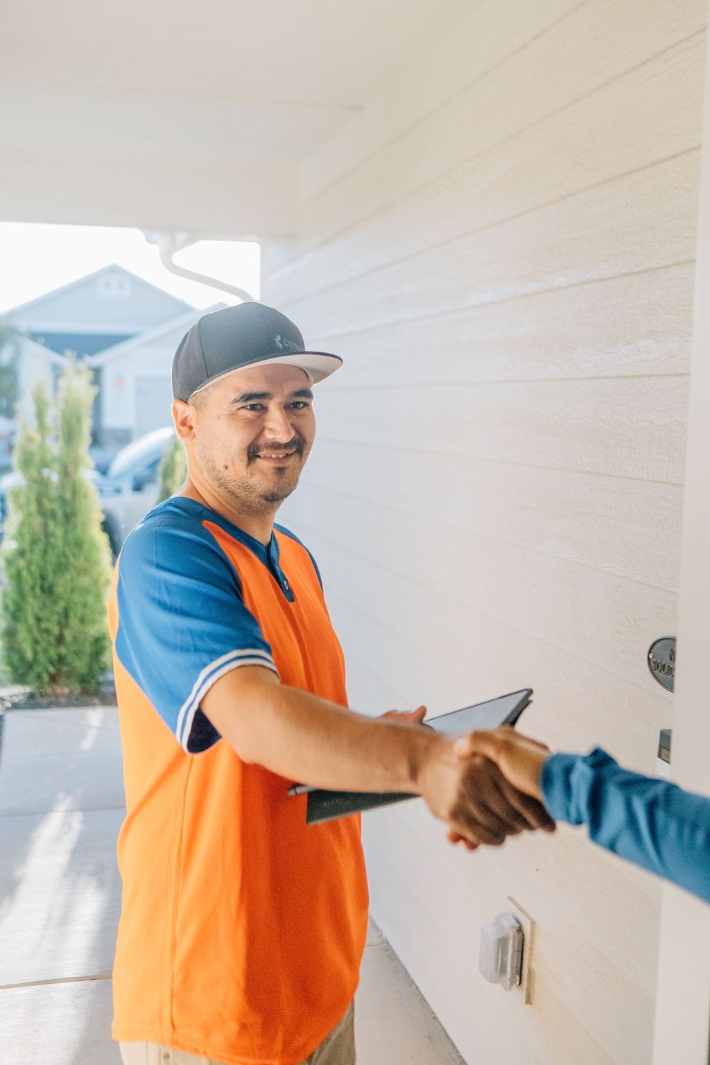 A delivery man is shaking hands with a customer while holding a clipboard.