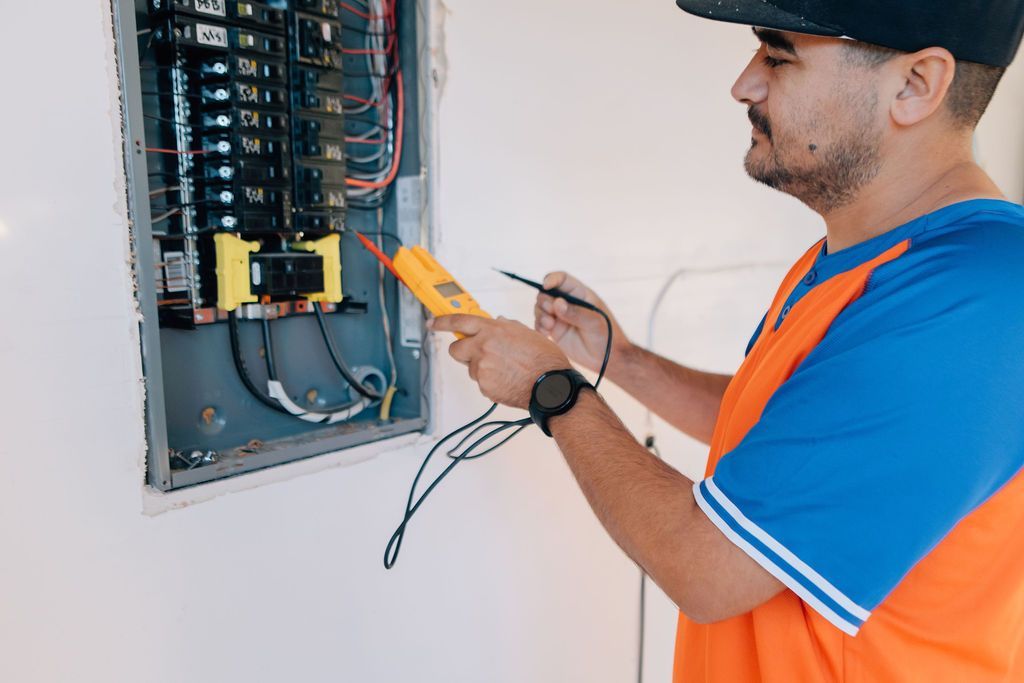 A man is working on an electrical panel with a multimeter.
