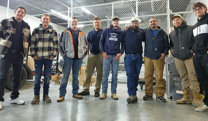 A group of men are posing for a picture in a warehouse.