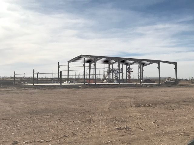 A building under construction in the middle of a dirt field