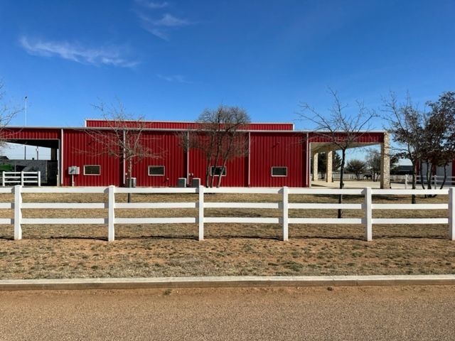 A red barn with a white fence in front of it