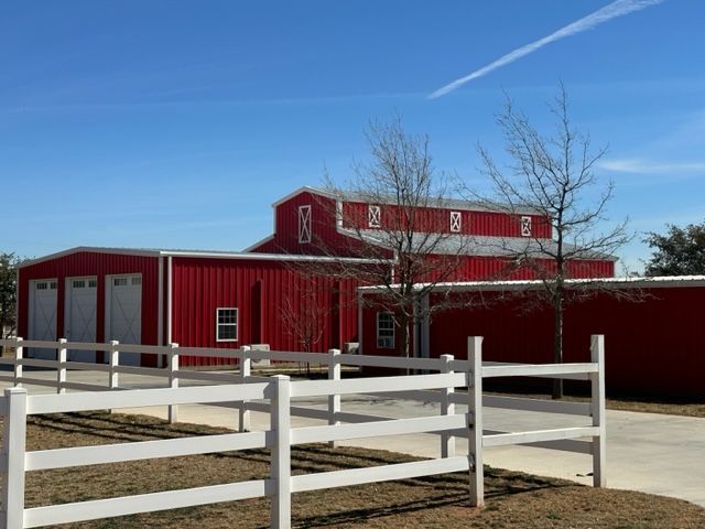A red barn with a white fence in front of it