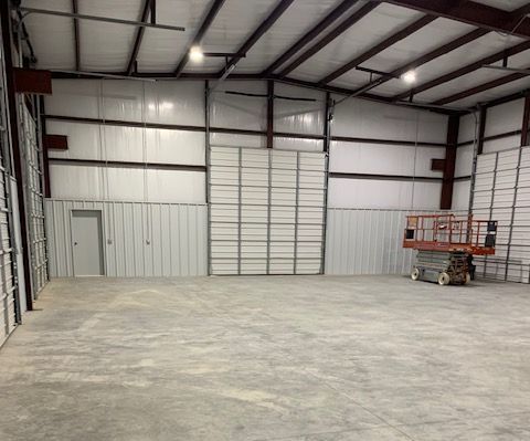 An empty warehouse with a scissor lift in the middle of it.