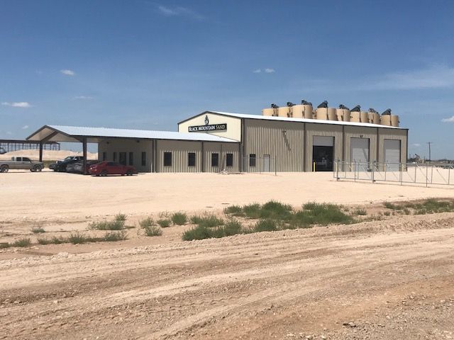 A large building is sitting in the middle of a dirt field.