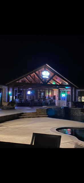 A large house with a pool in front of it at night.