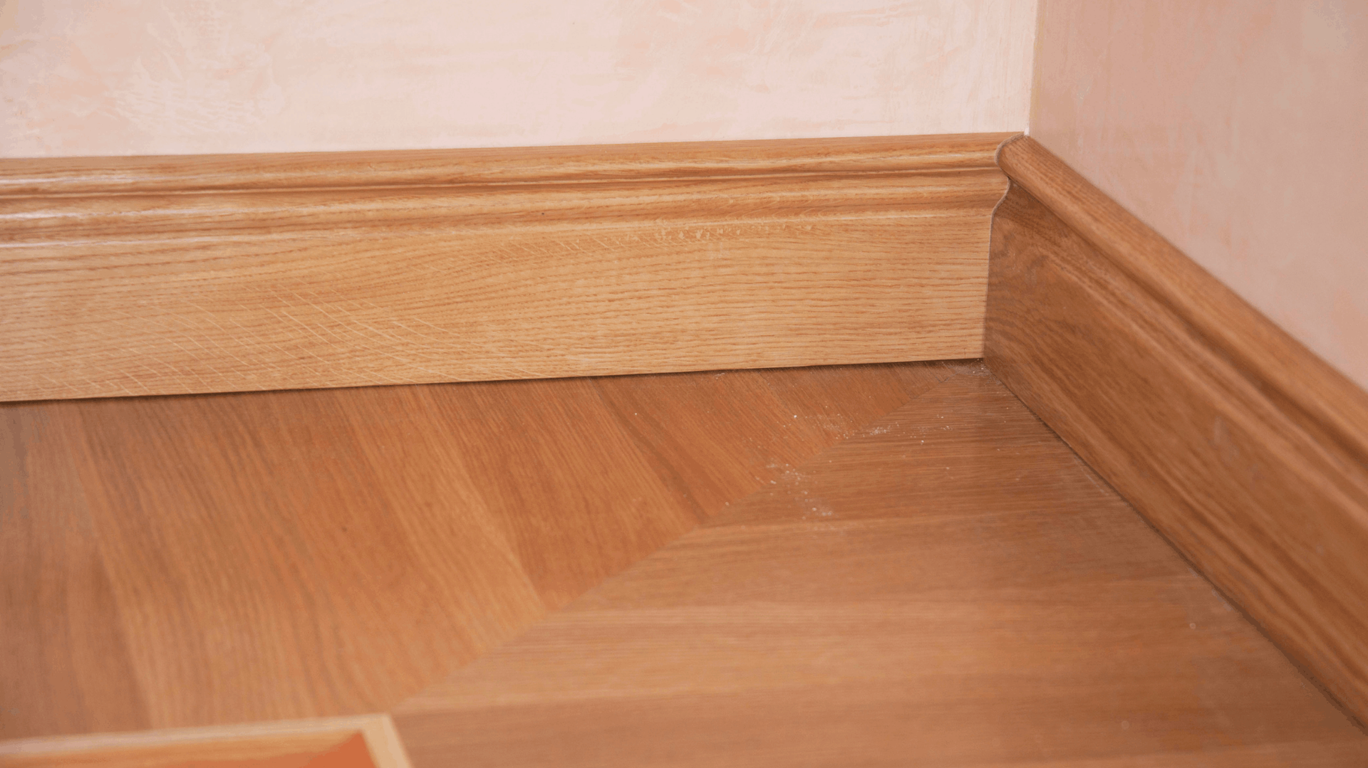 Wooden Floor and Baseboard Corner, Light Wood Color Against a Light Pink Wall — Ericson Constructions in Mareeba, QLD