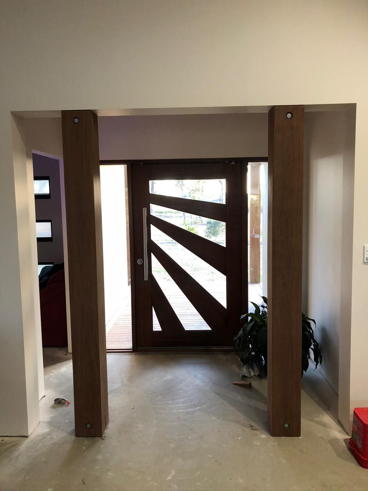 Entrance doorway with wooden door and decorative wooden pillars.