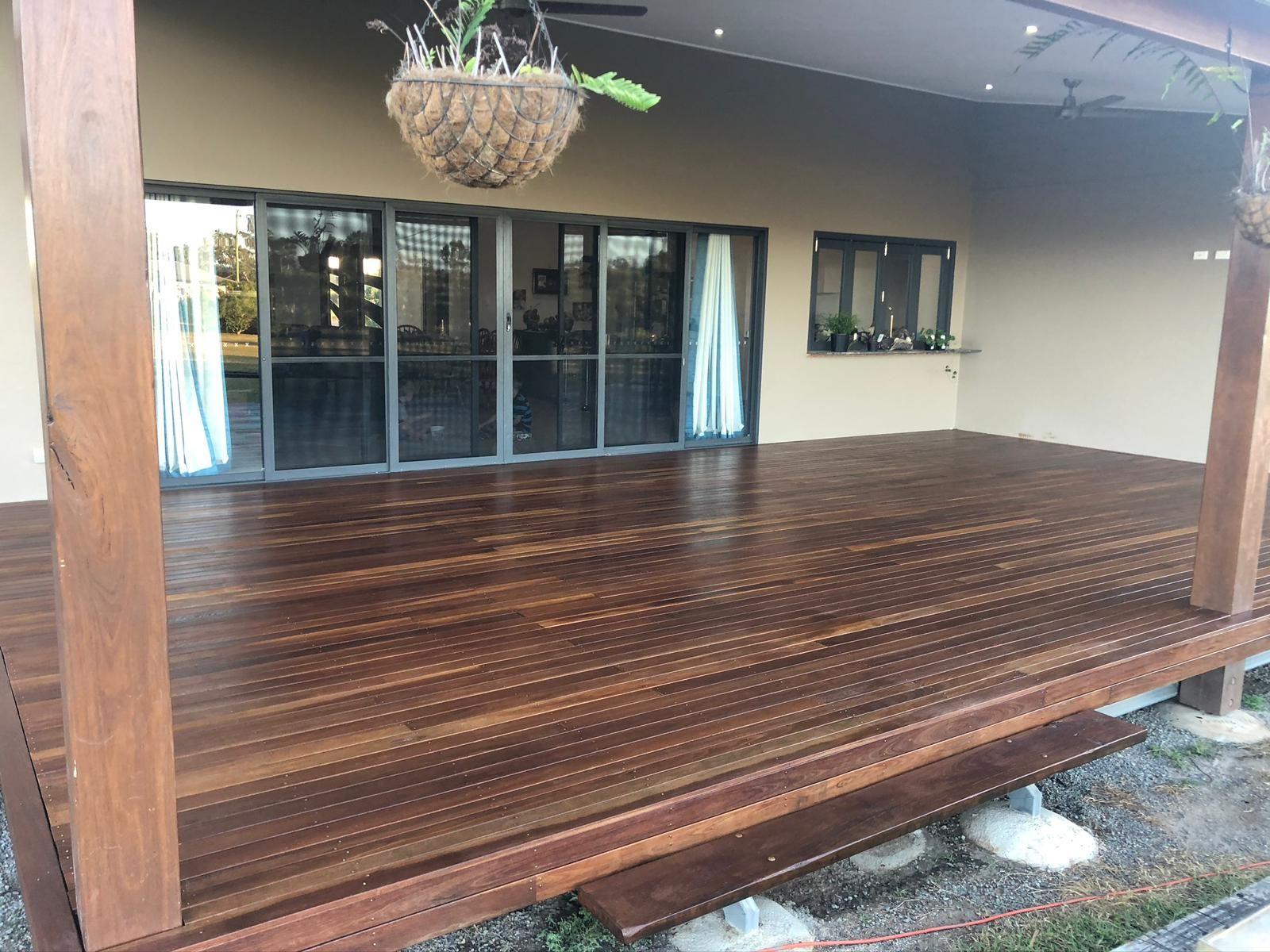 Wooden Deck With Glass Sliding Doors, Hanging Plant, and a Neutral-toned Building — Ericson Constructions in Mareeba, QLD