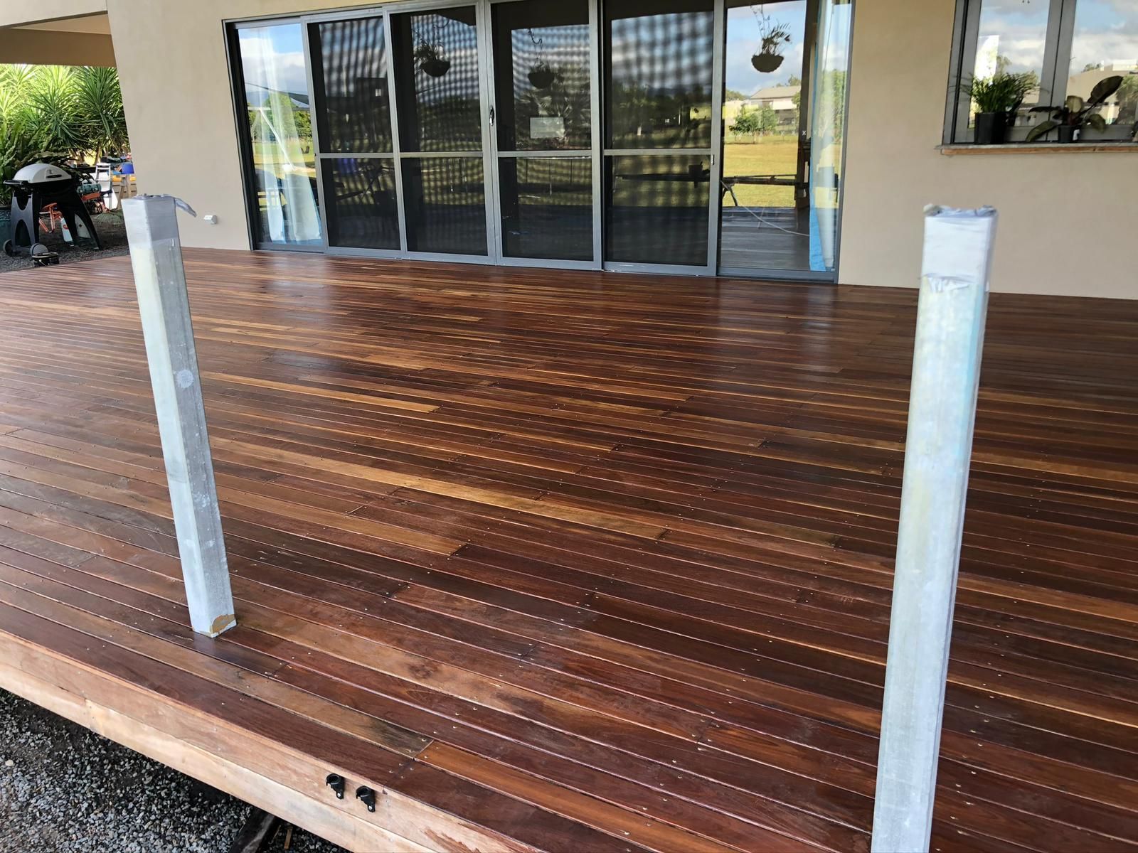 Wooden Deck With Two Silver Posts in Front of a House With Glass Doors — Ericson Constructions in Mareeba, QLD