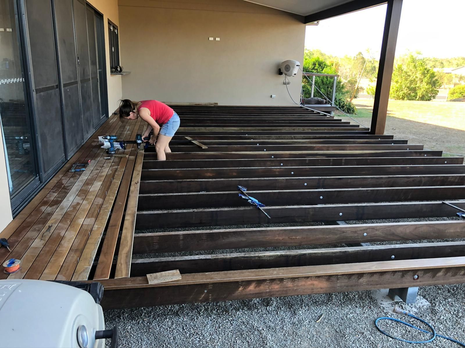Woman Installing Wooden Deck Boards on an Outdoor Patio — Ericson Constructions in Mareeba, QLD
