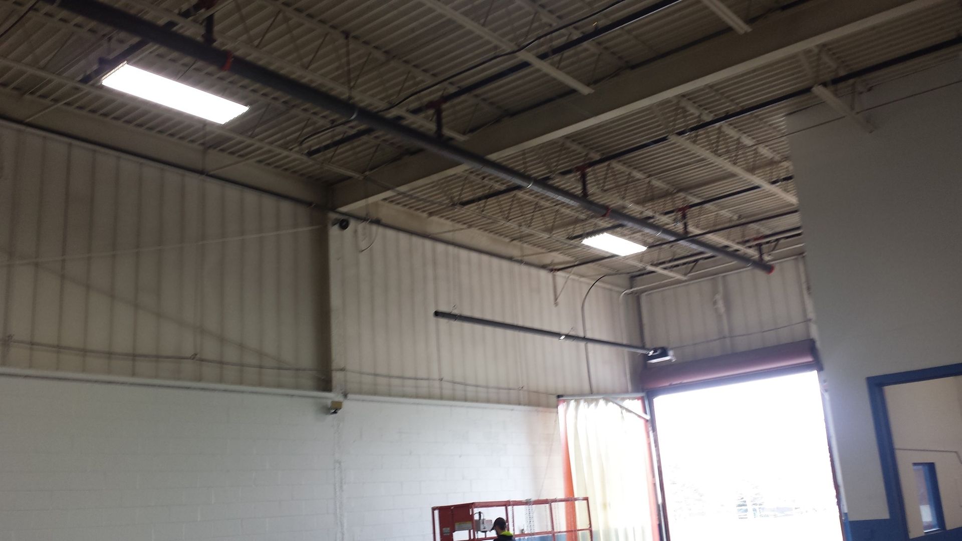 a warehouse with a large door and a lot of lights on the ceiling