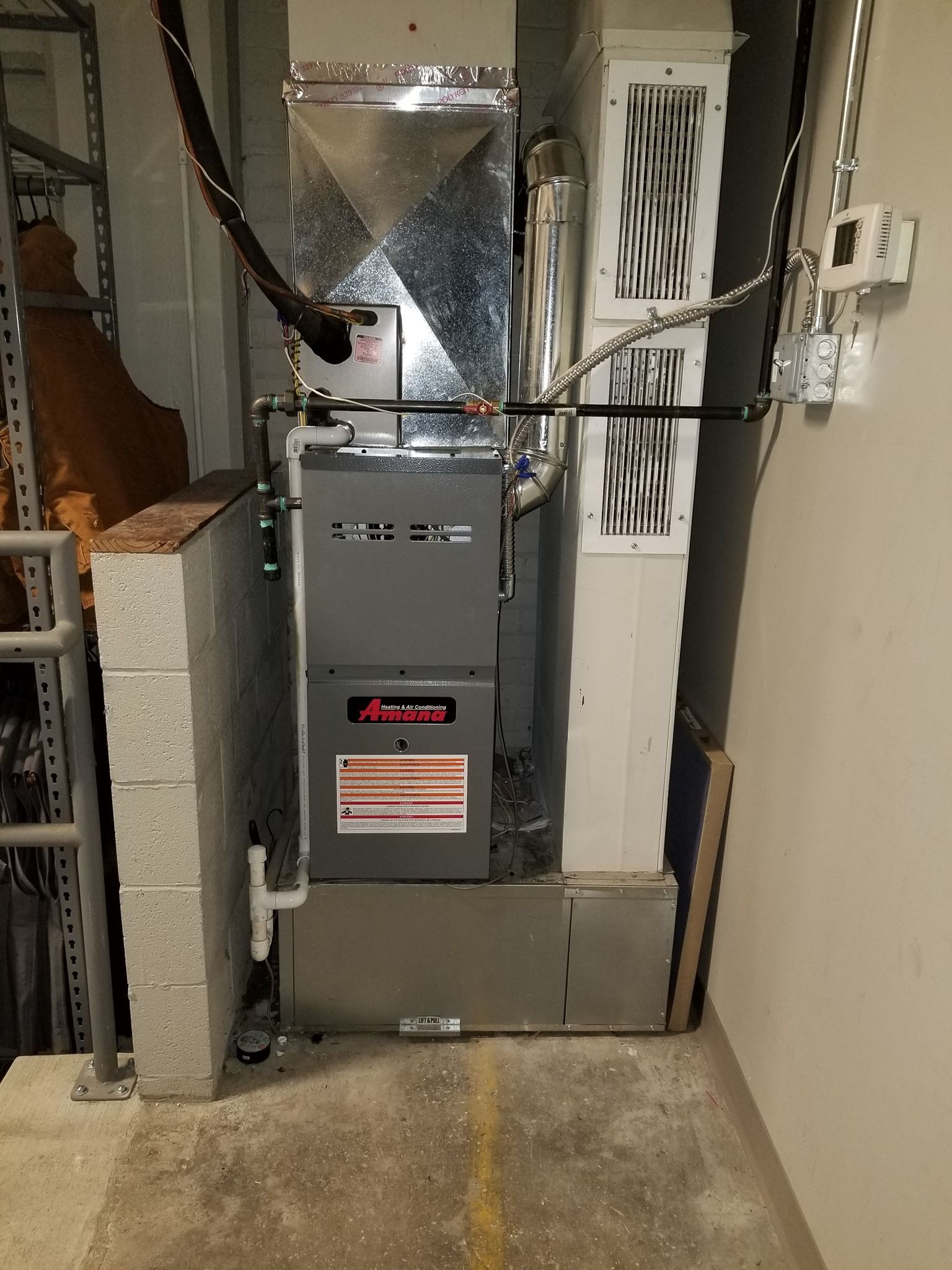 a furnace is sitting in a room next to a ladder .