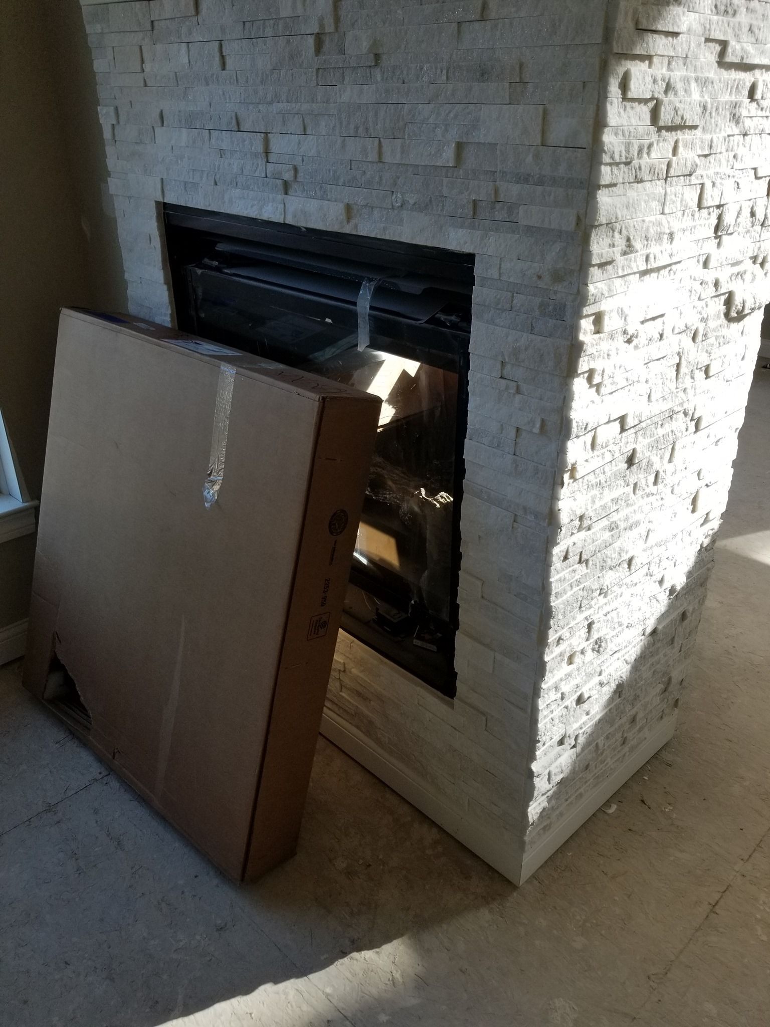 a cardboard box is sitting in front of a fireplace .
