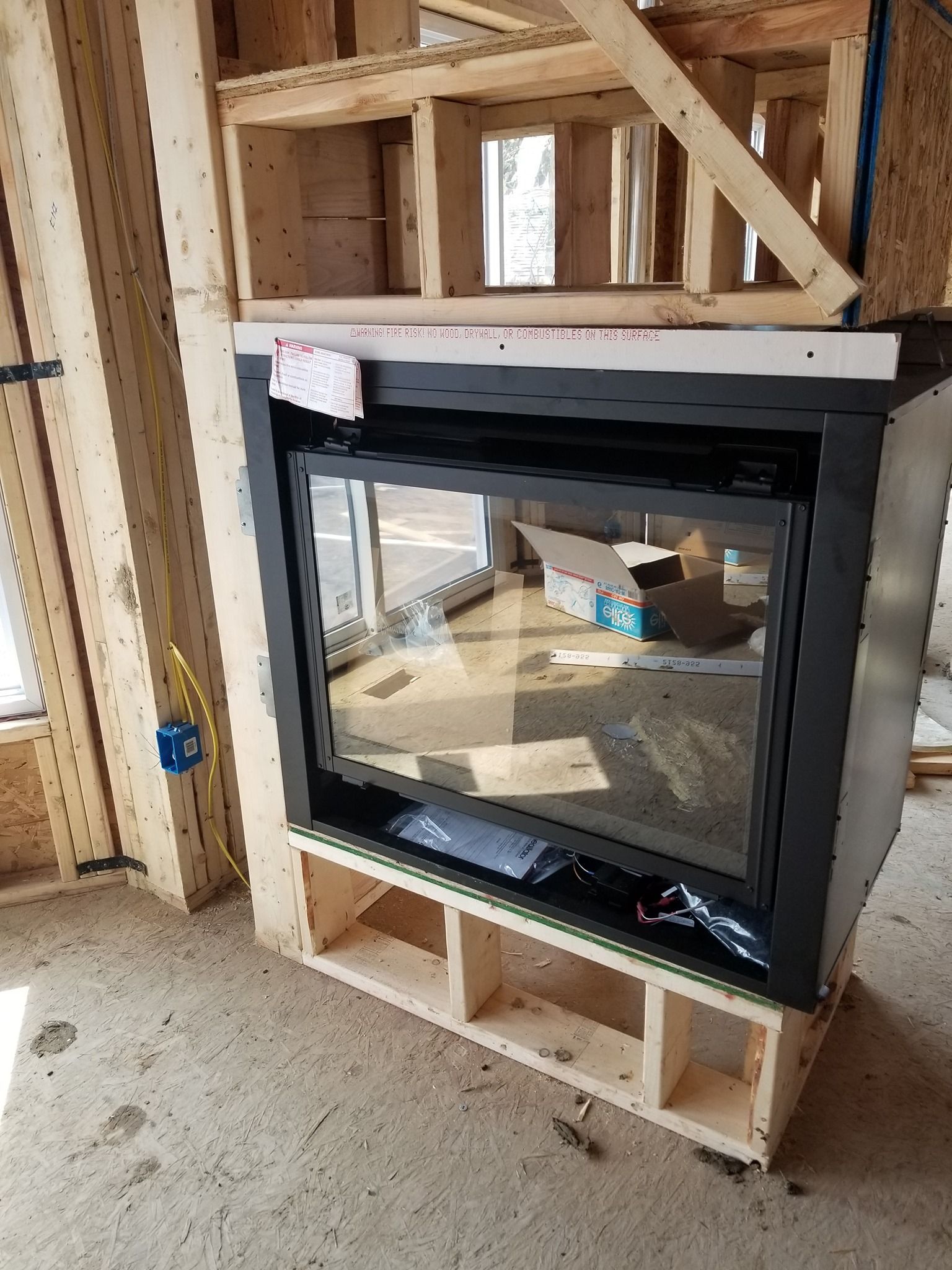 a fireplace is sitting on top of a wooden shelf in a room under construction .