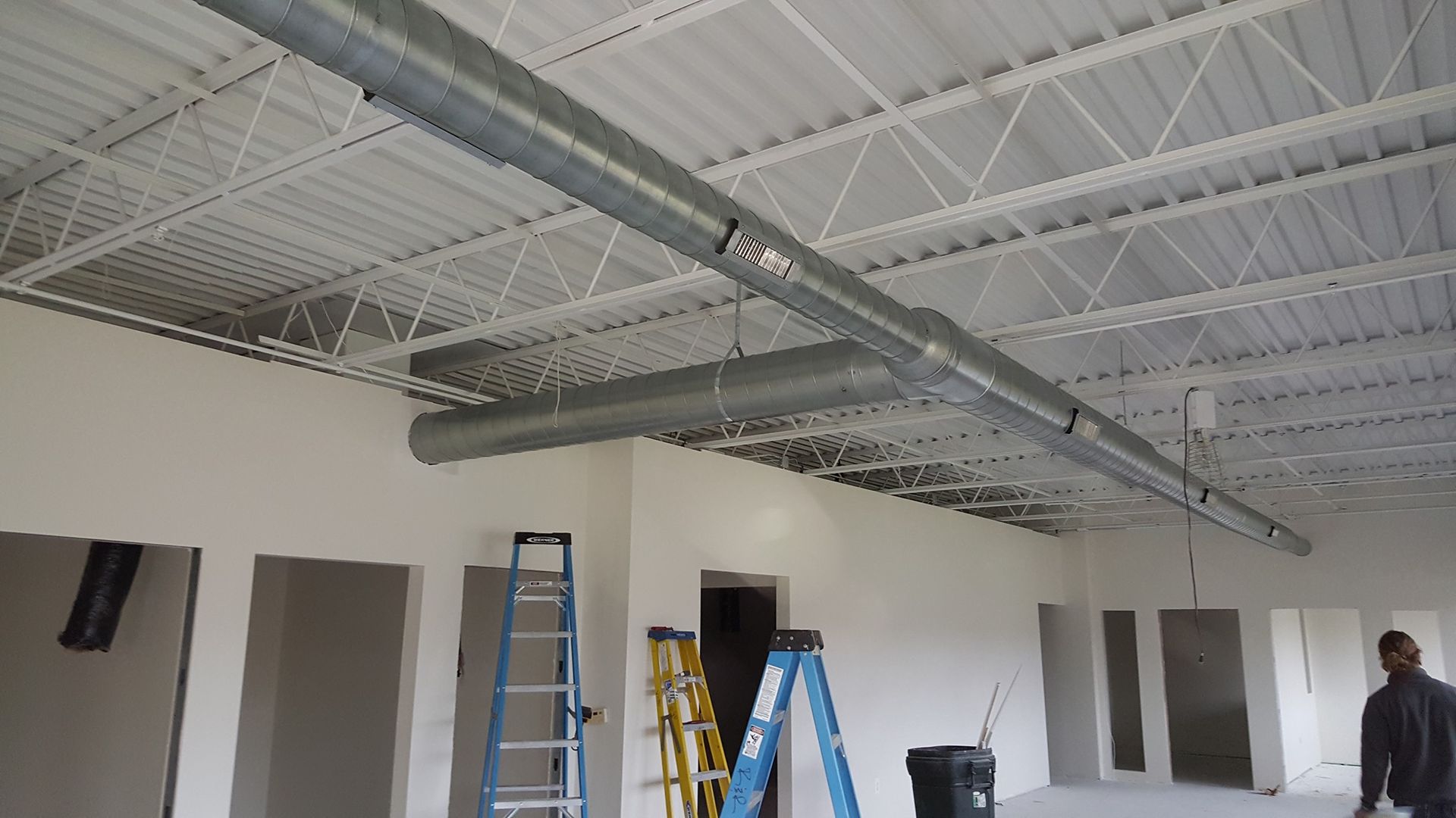 a man is standing in an empty room with a ladder .