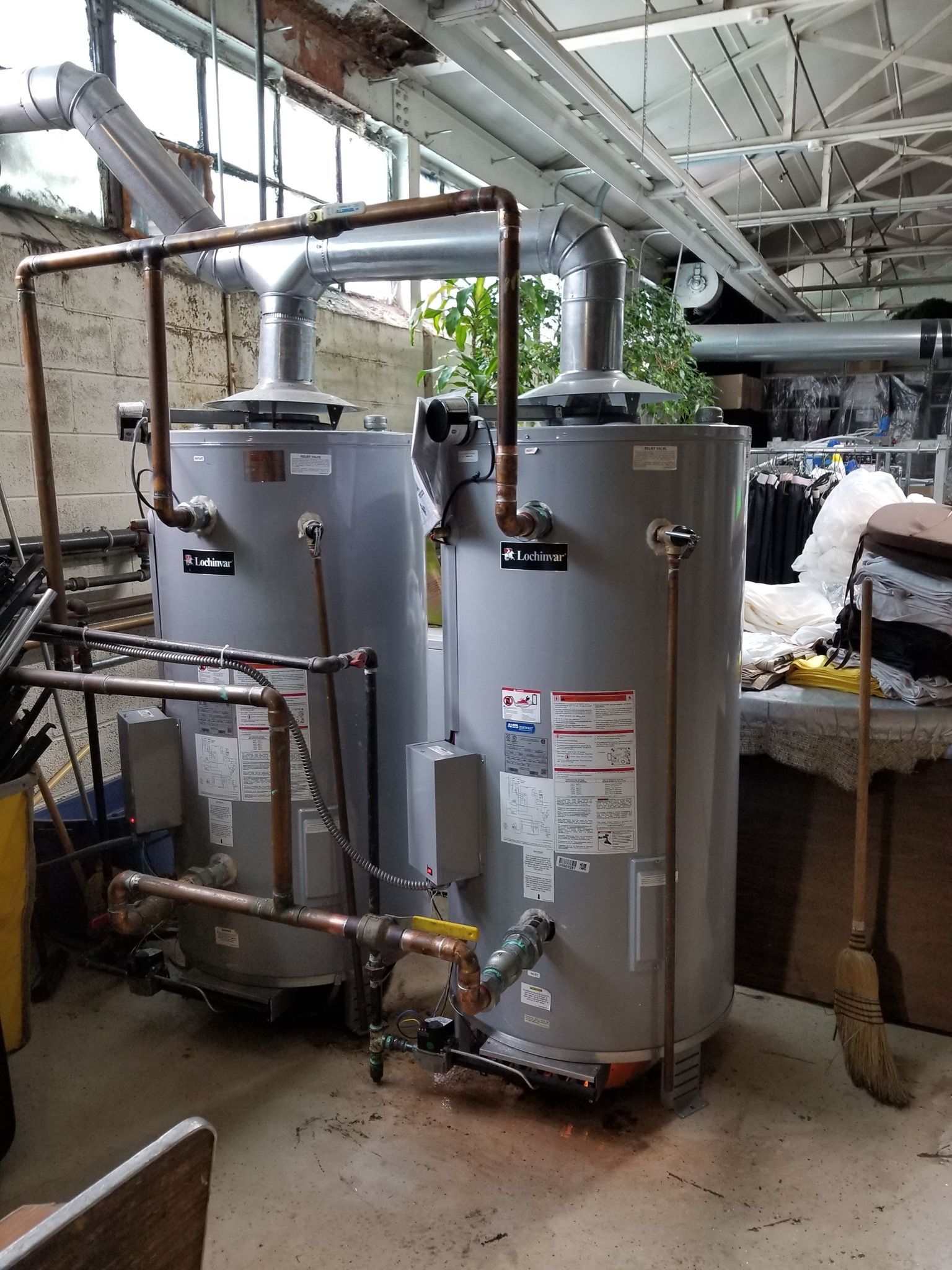 two water heaters are sitting next to each other in a room .