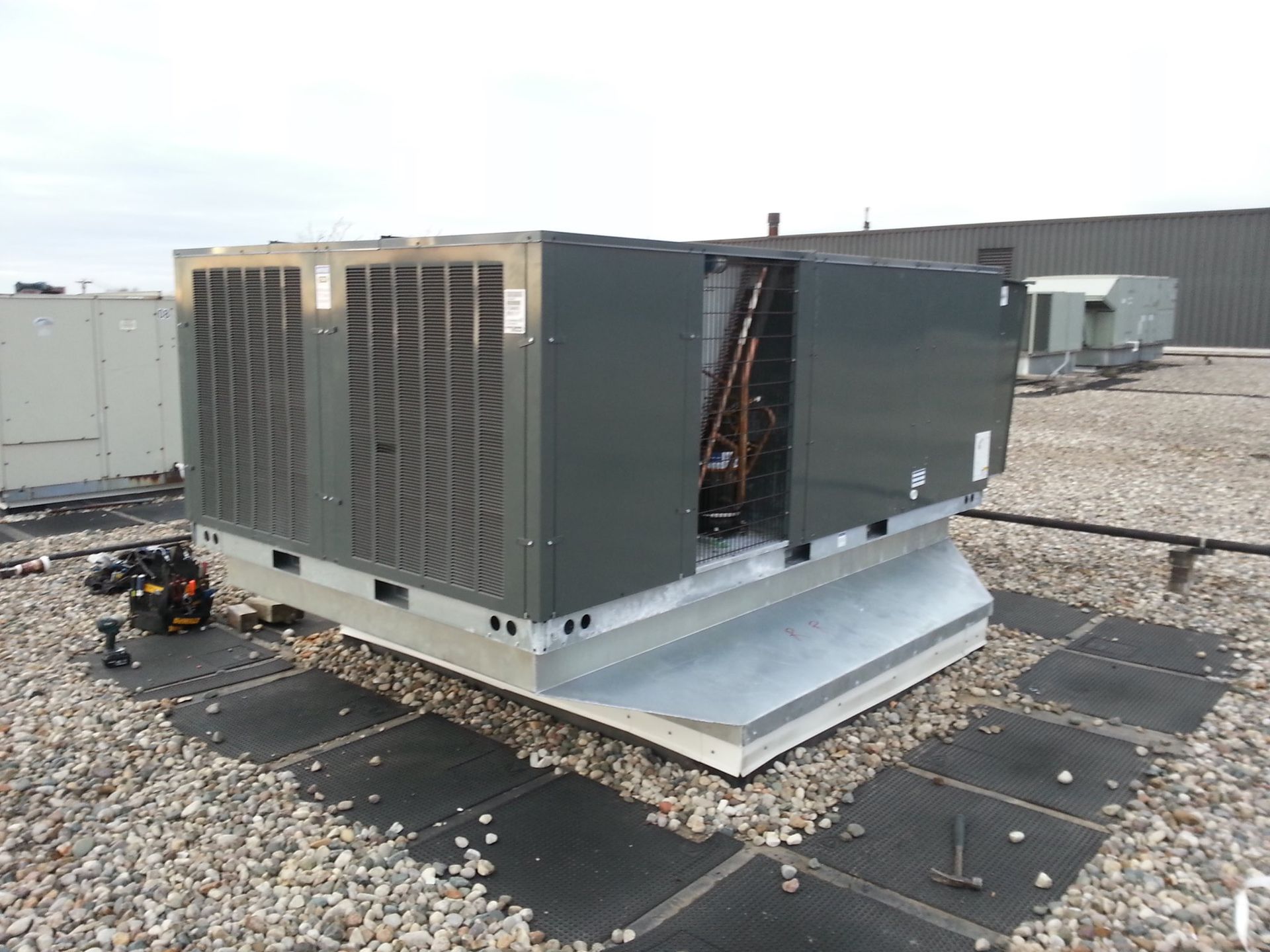 a large air conditioner is sitting on top of a gravel covered roof .