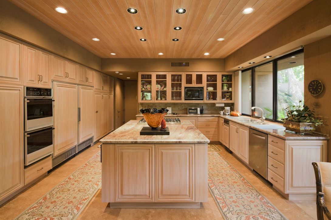Spacious modern kitchen with a central island, light wood cabinets, and large windows letting in natural light