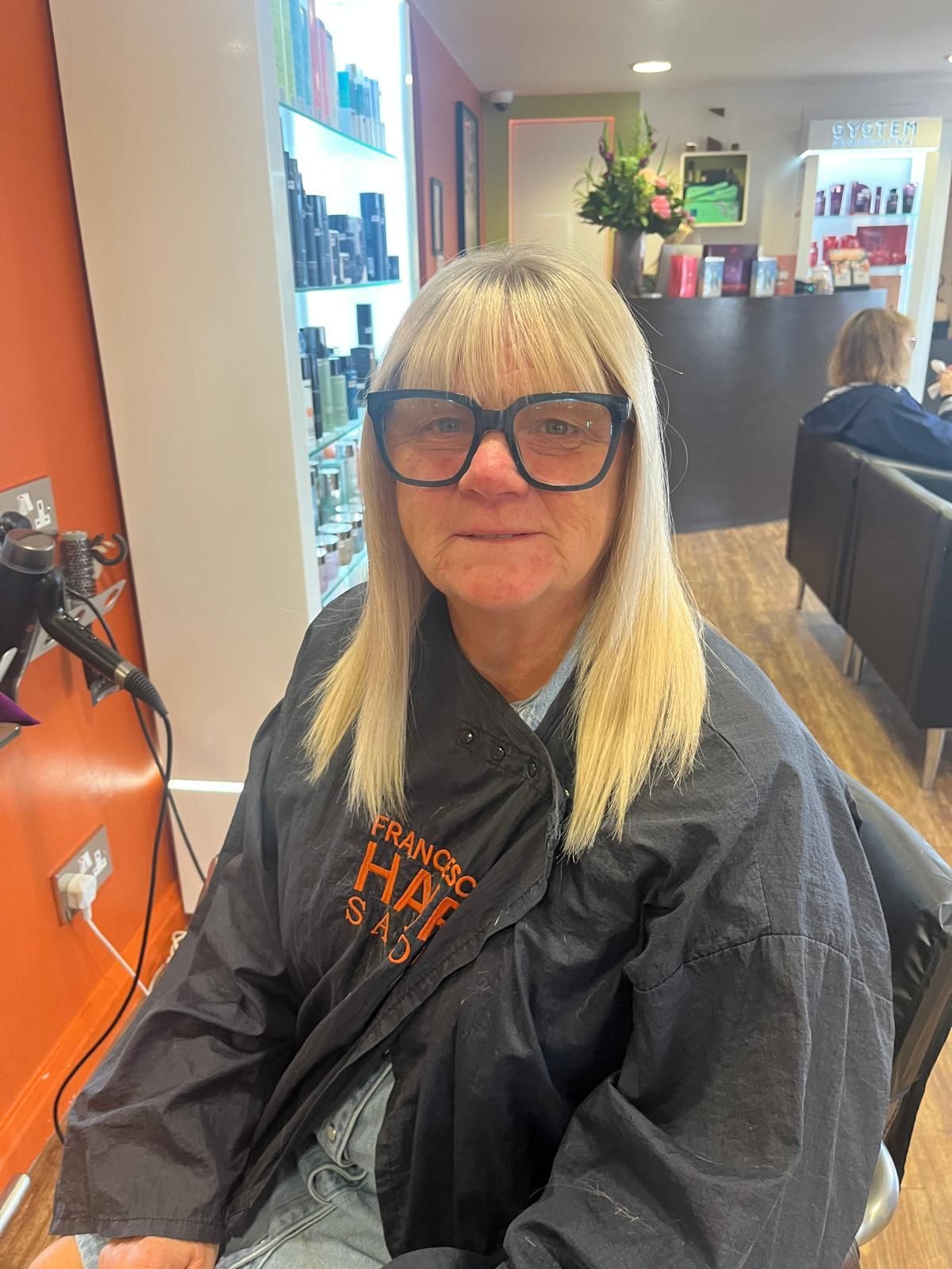 Client wearing a straight blonde hair topper with a full fringe for natural-looking coverage at The Roche Hair Experience in Stafford.