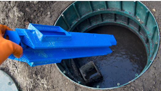 A person is holding a blue object in a hole in the ground.