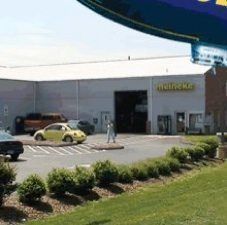 A yellow car is parked in a parking lot in front of a building.
