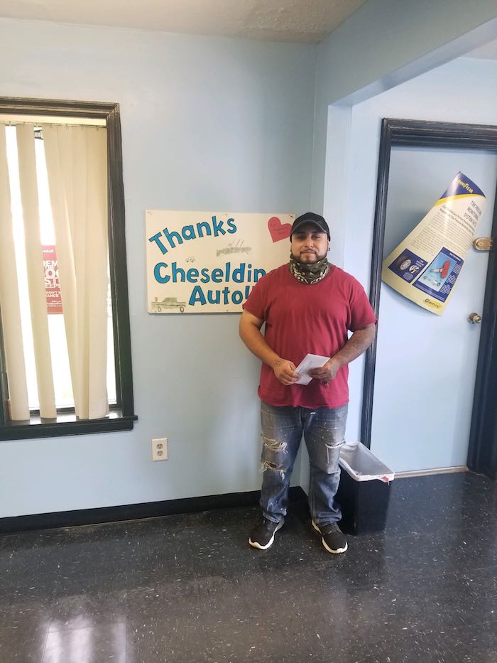 A man in a red shirt is standing in front of a sign that says thanks.