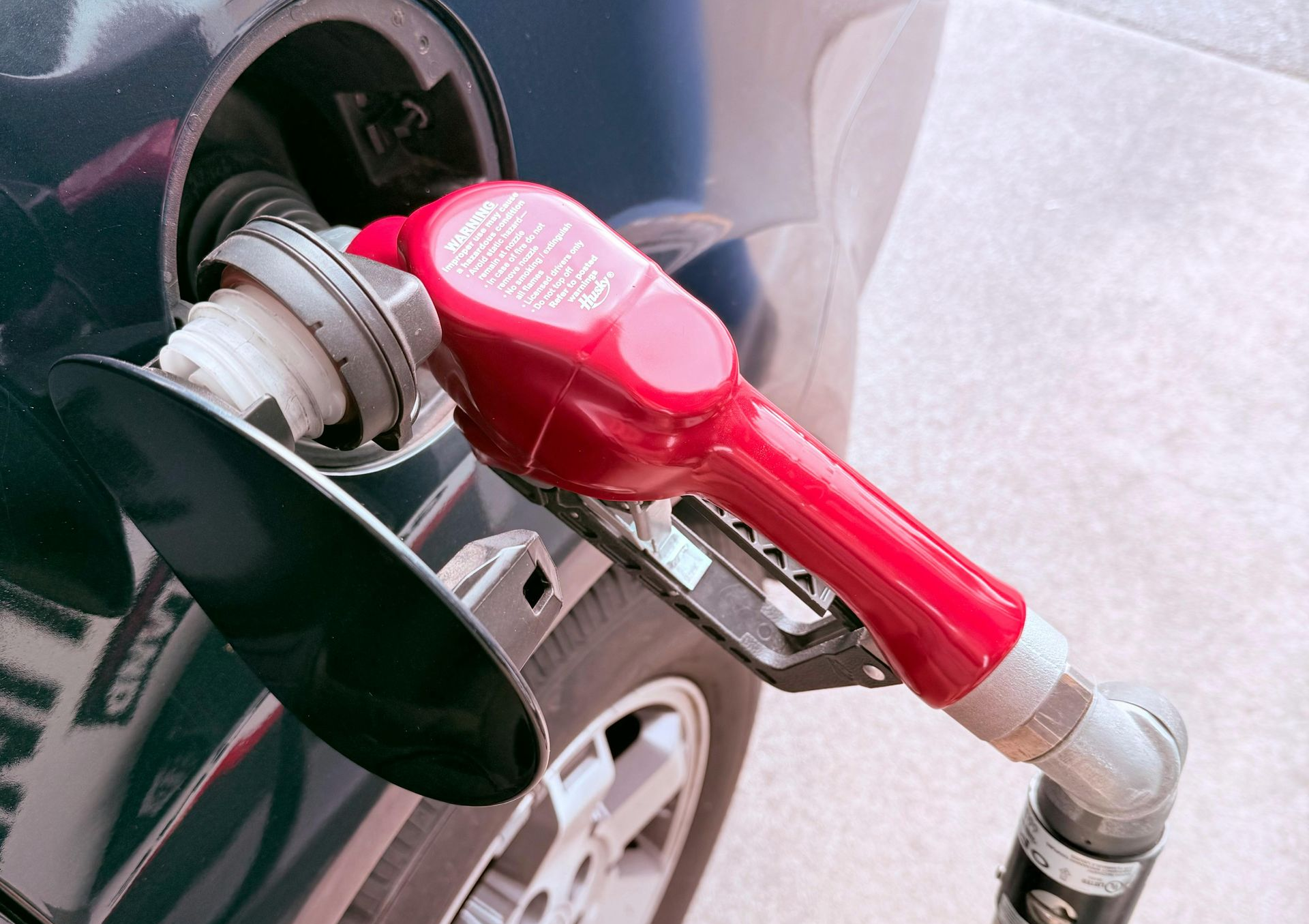 Red fuel pump nozzle inserted into a car’s gas tank opening