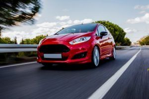 A red car is driving down a highway.