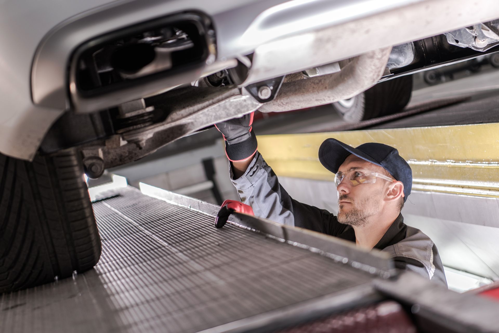 A man is working under a car in a garage.