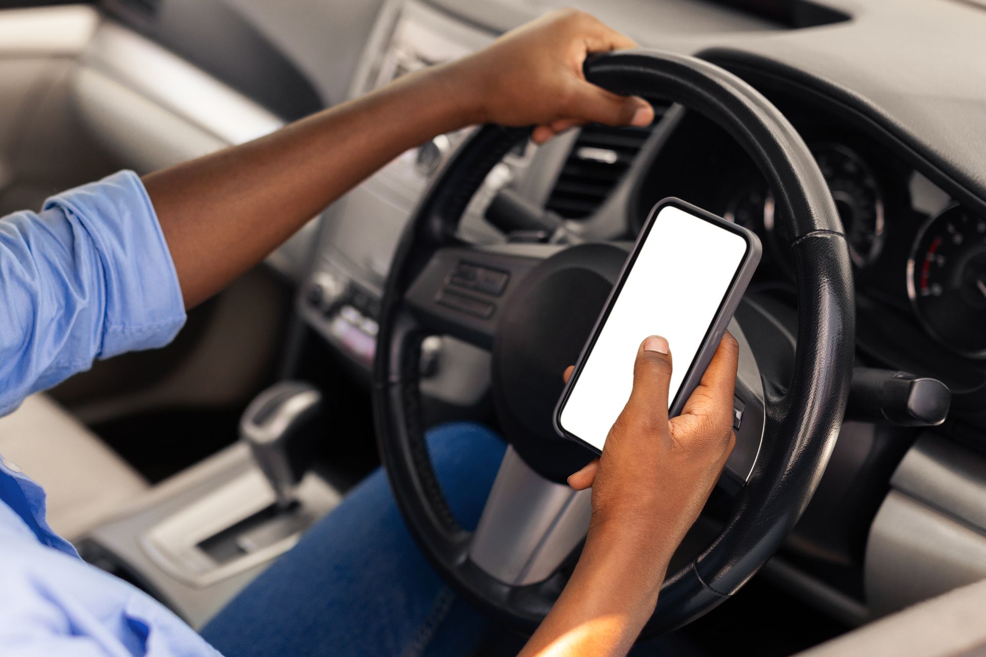 A person is using a cell phone while driving a car.