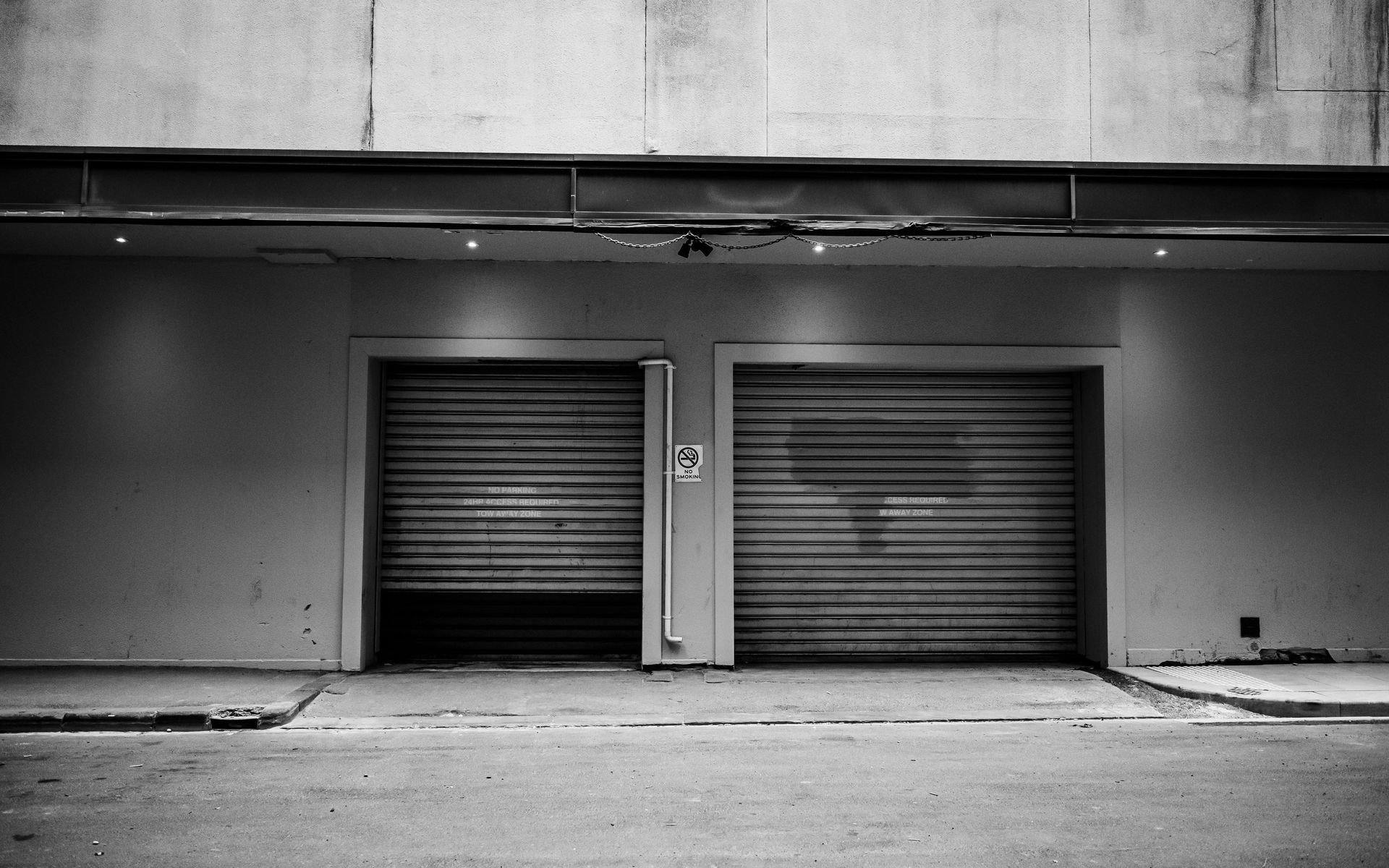 Two closed roll-up garage doors on a gray industrial building facade