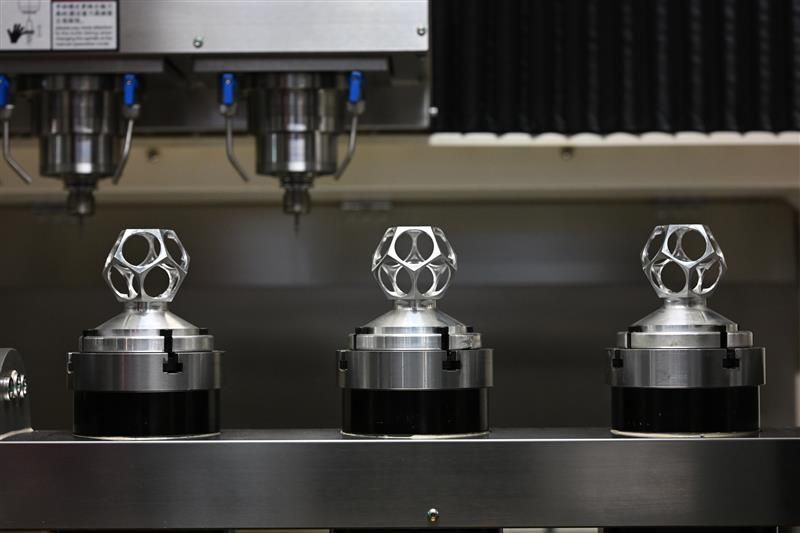 Three metal cylinders positioned on a machine, showcasing the process of metal injection molding.