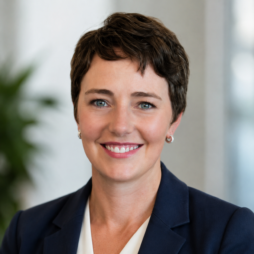 Smiling professional in a navy blazer against a soft, blurred office background