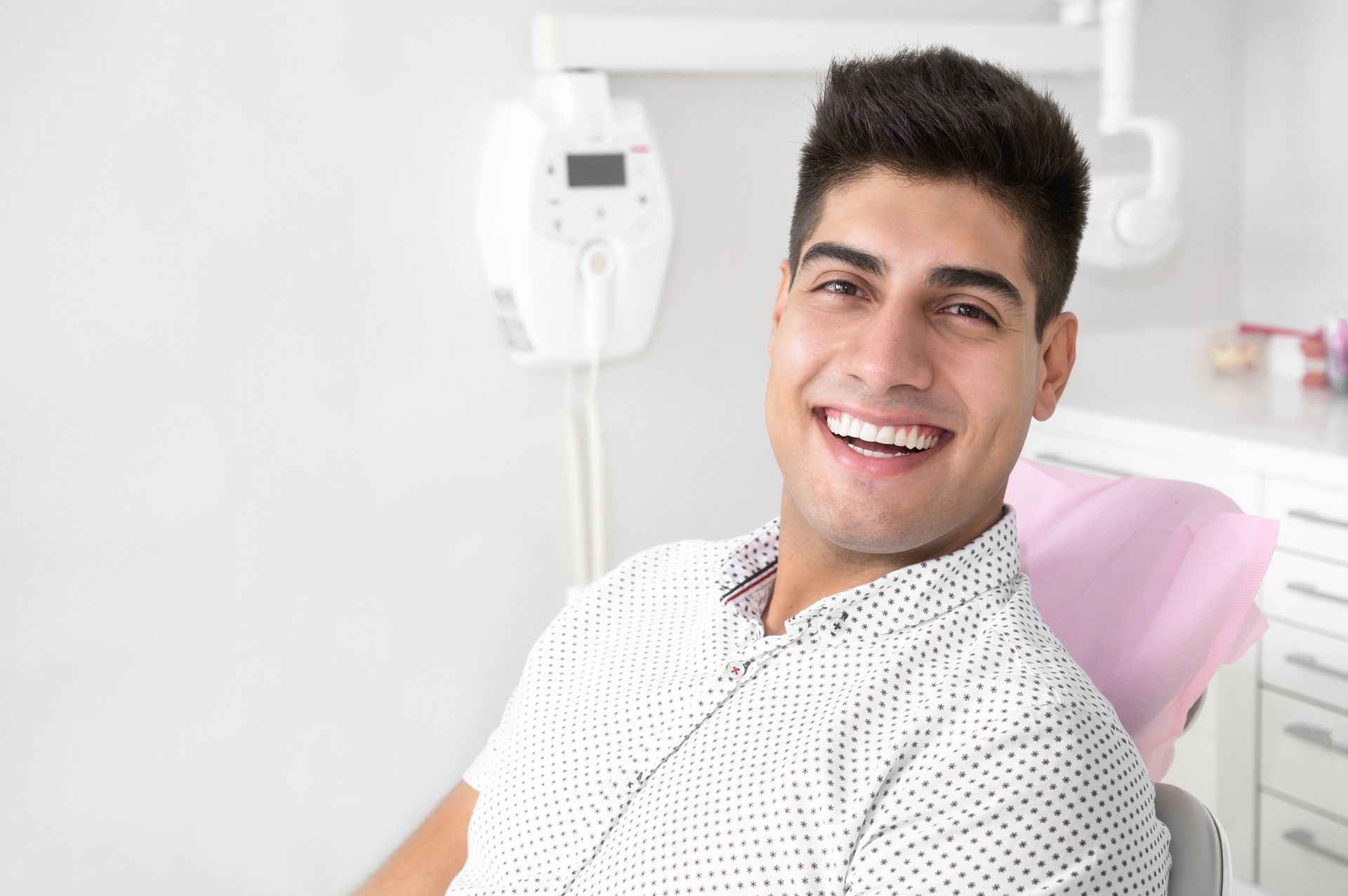 Smiling man seated in a dental chair in a bright clinic
