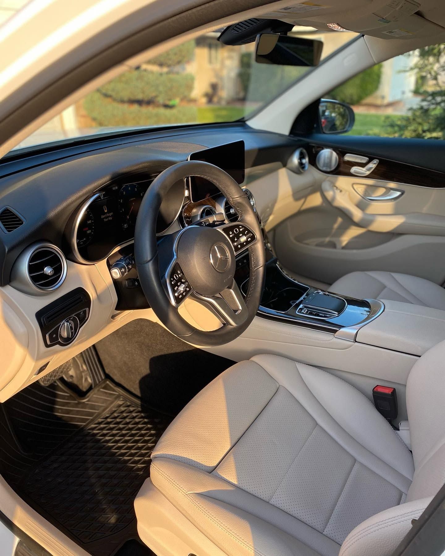 Car interior with black steering wheel, beige seats, and dashboard in sunlight