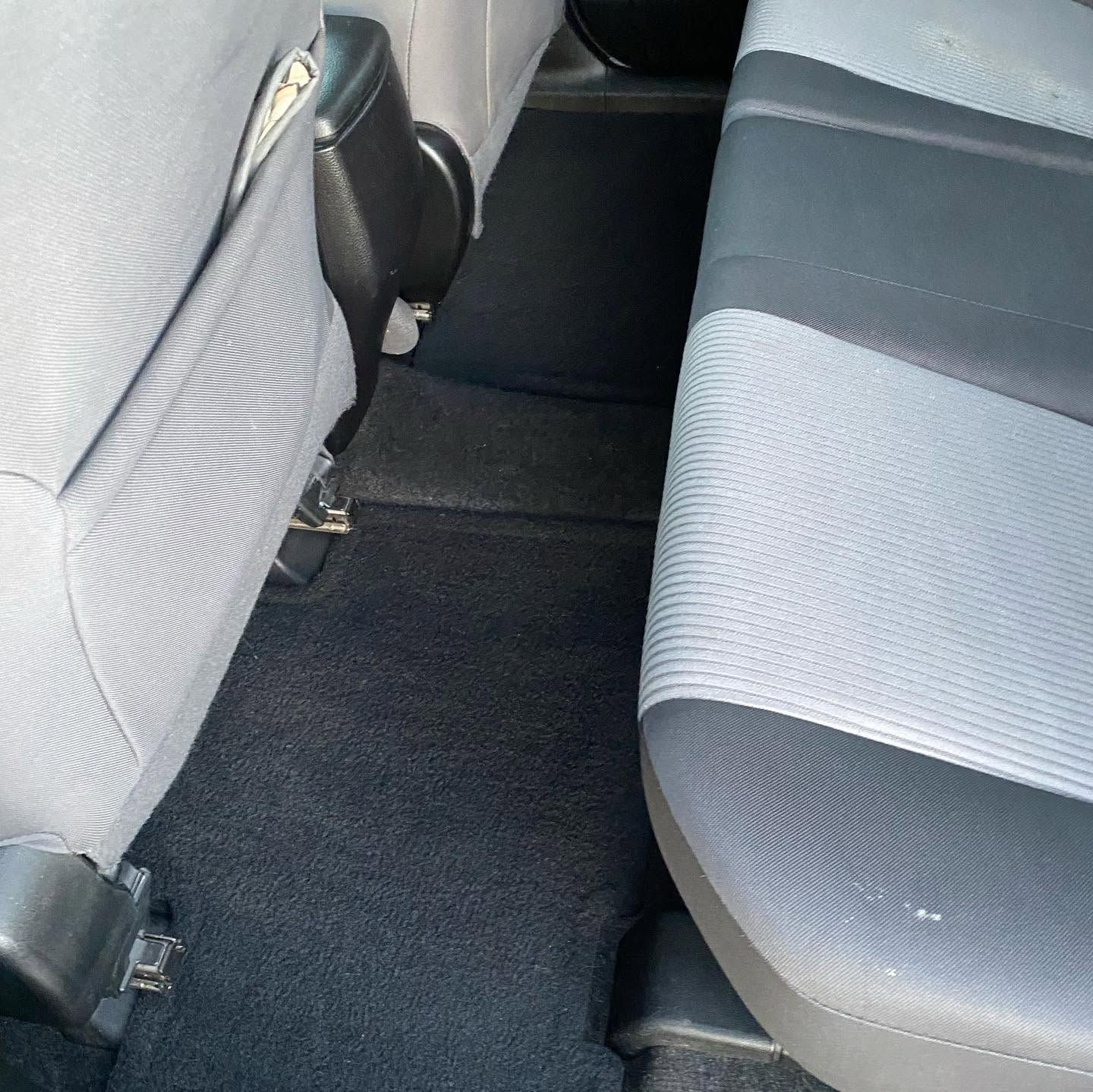 Back seat of a car with gray fabric seats and black floor mats
