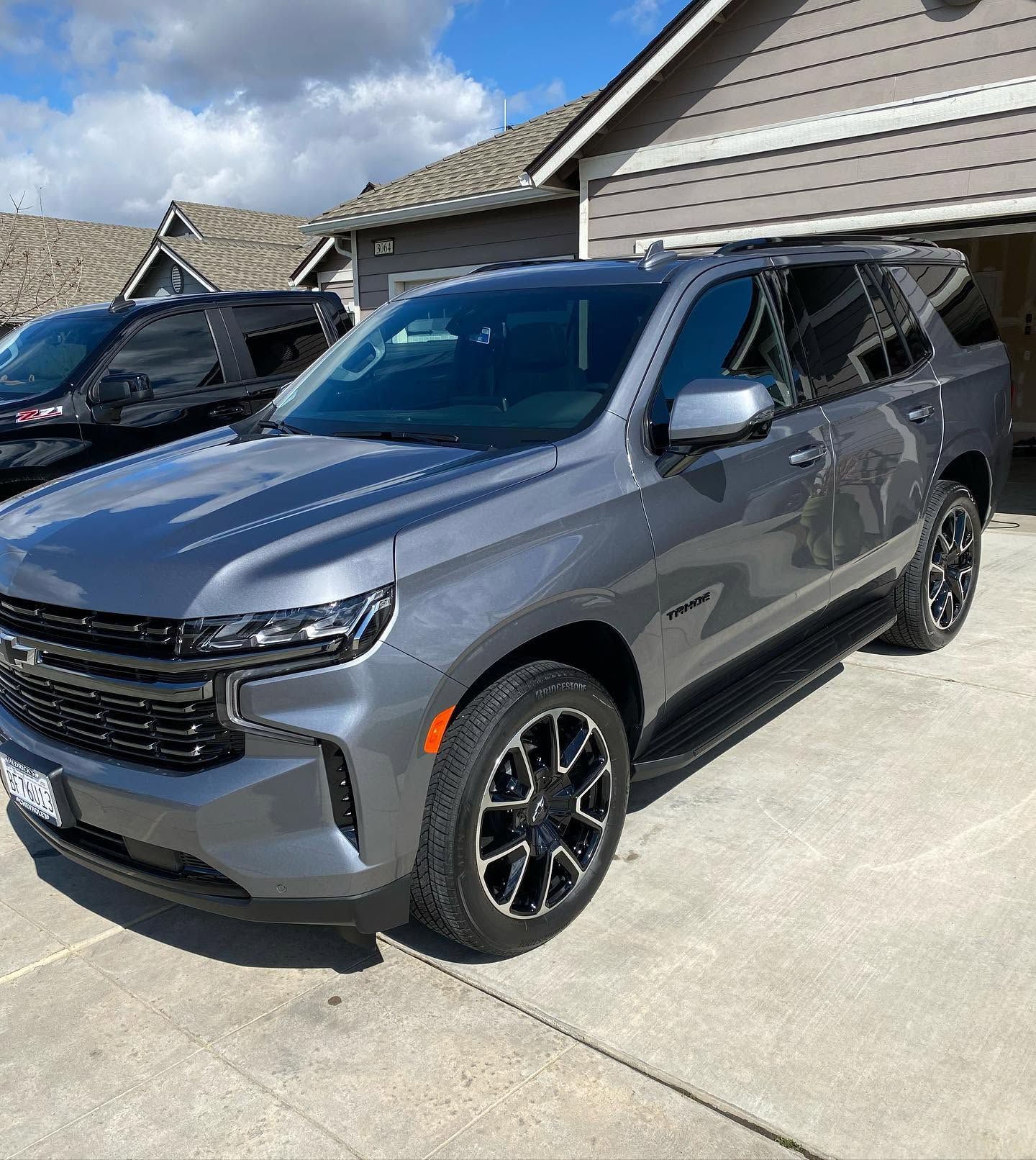 Gray SUV parked in a driveway beside a house on a sunny day