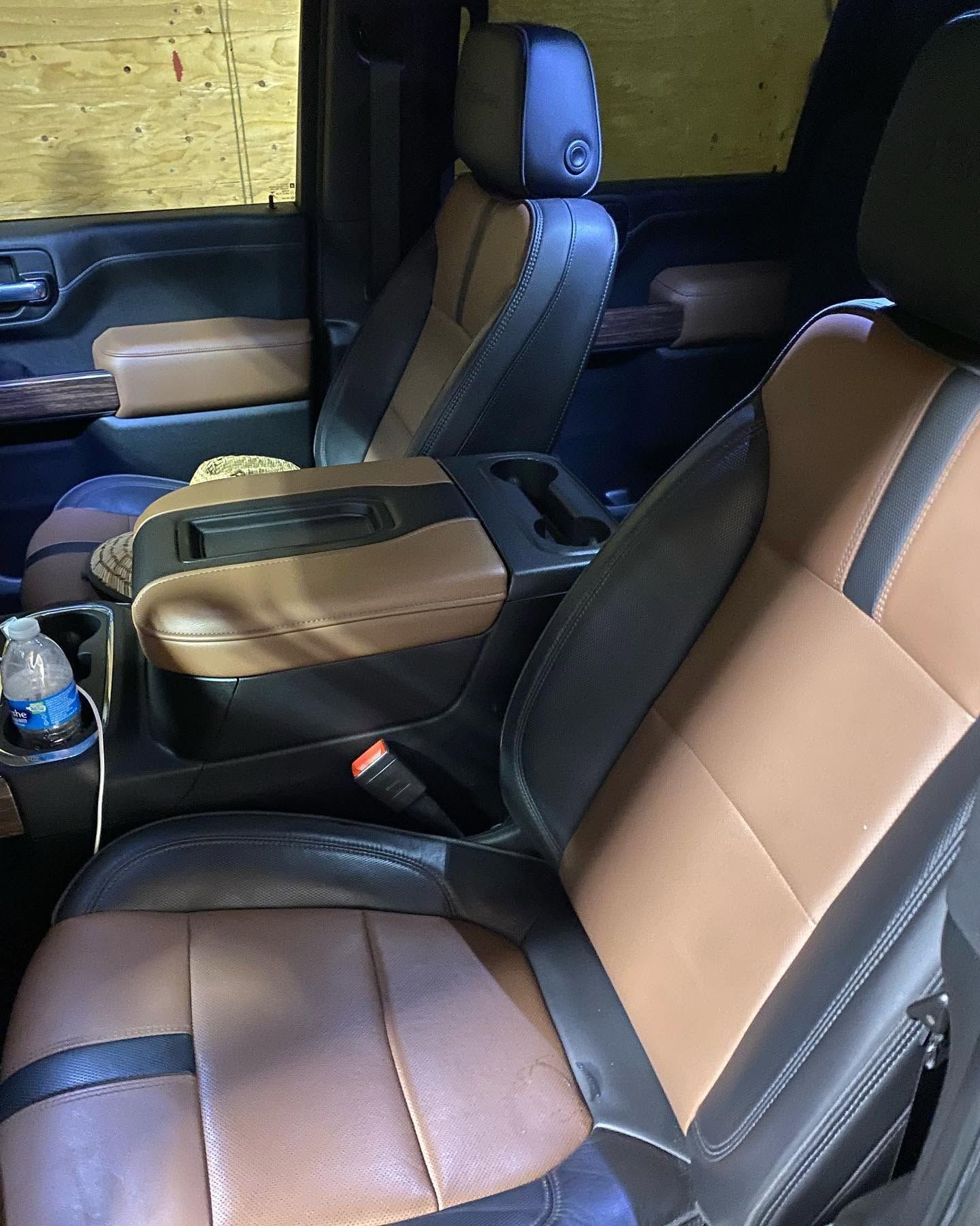Black and tan car interior with front seats, center console, and water bottle on the floor