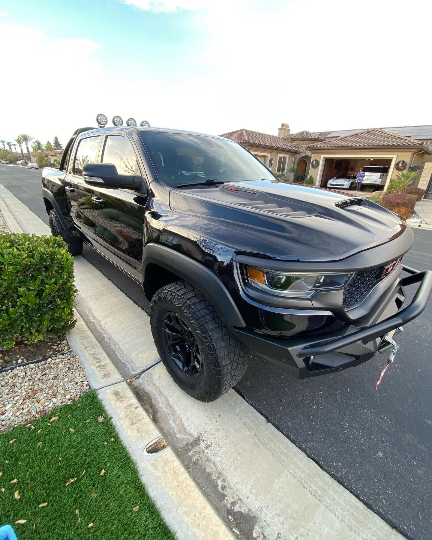 Black pickup truck parked by a curb in a suburban parking lot, angled toward the camera.