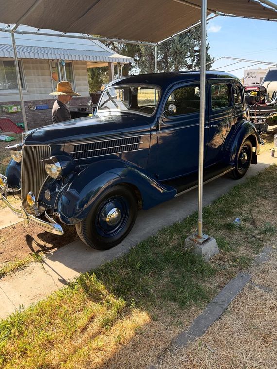 Vintage dark blue classic car parked under a canopy at a car show