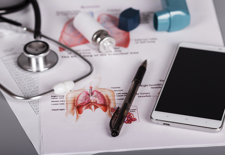 A stethoscope , a pen , a cell phone and asthma inhalers are on a table.