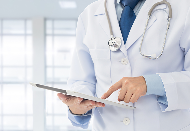 A doctor with a stethoscope around his neck is using a tablet computer.