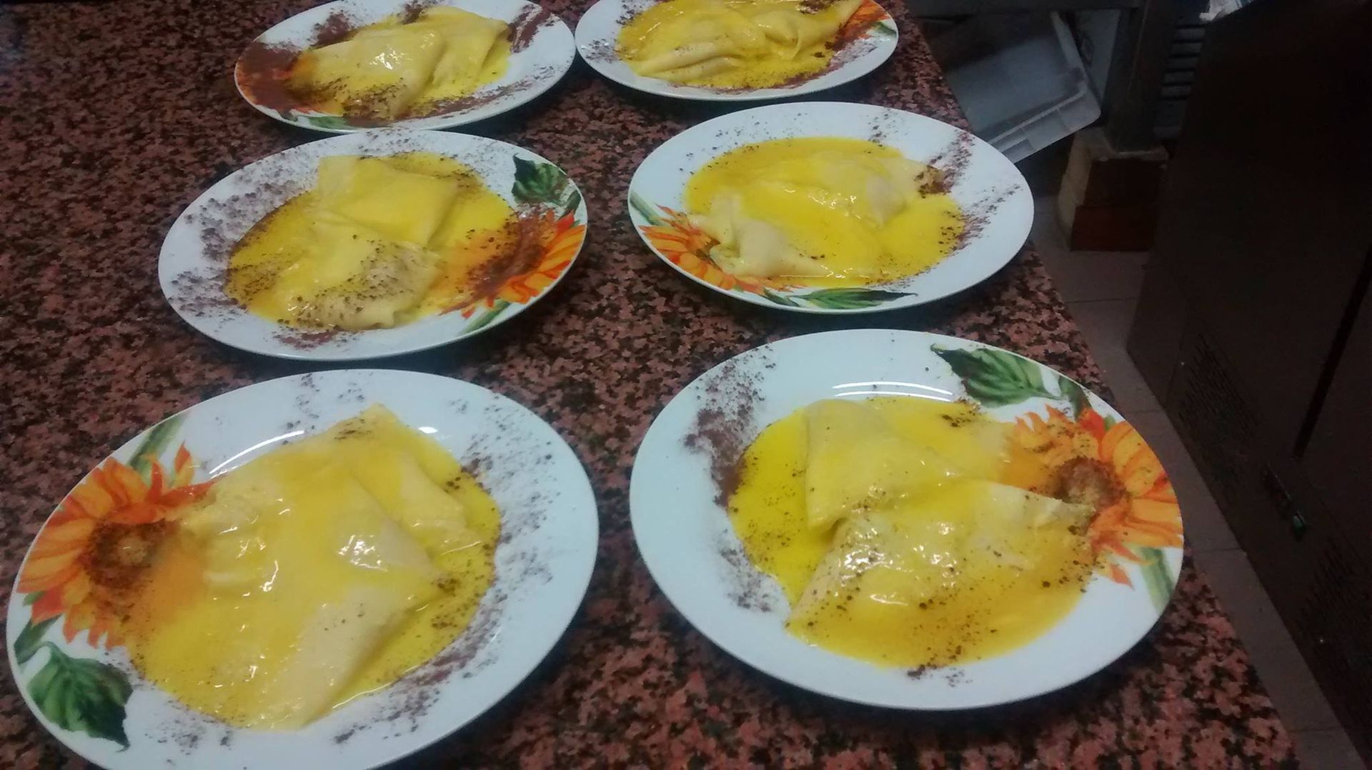 Sei piatti di dessert giallo su un piano di granito, ciascuno decorato con una guarnizione arancione.