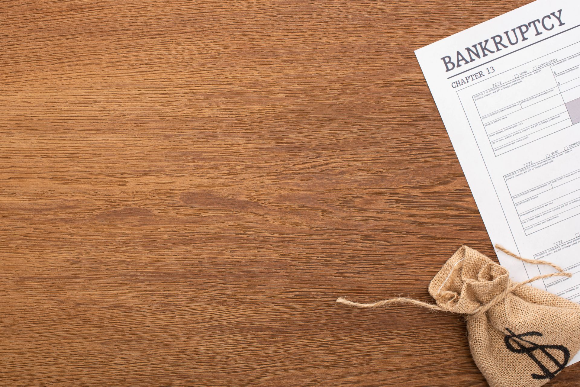 Bankruptcy document with a tied money bag on a wooden table, suggesting financial distress