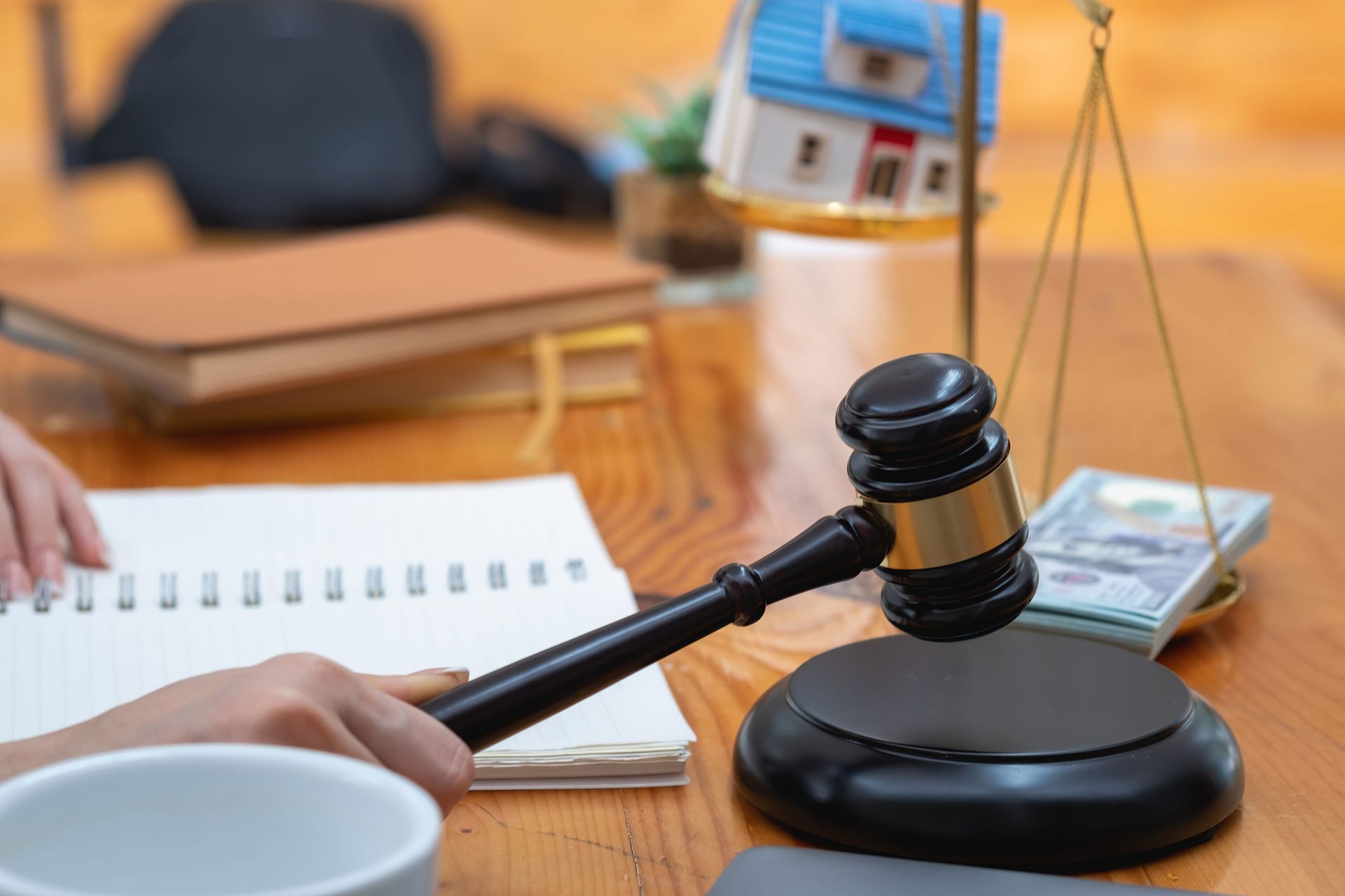 Gavel on a desk beside an open notebook and house model, suggesting a real estate legal meeting