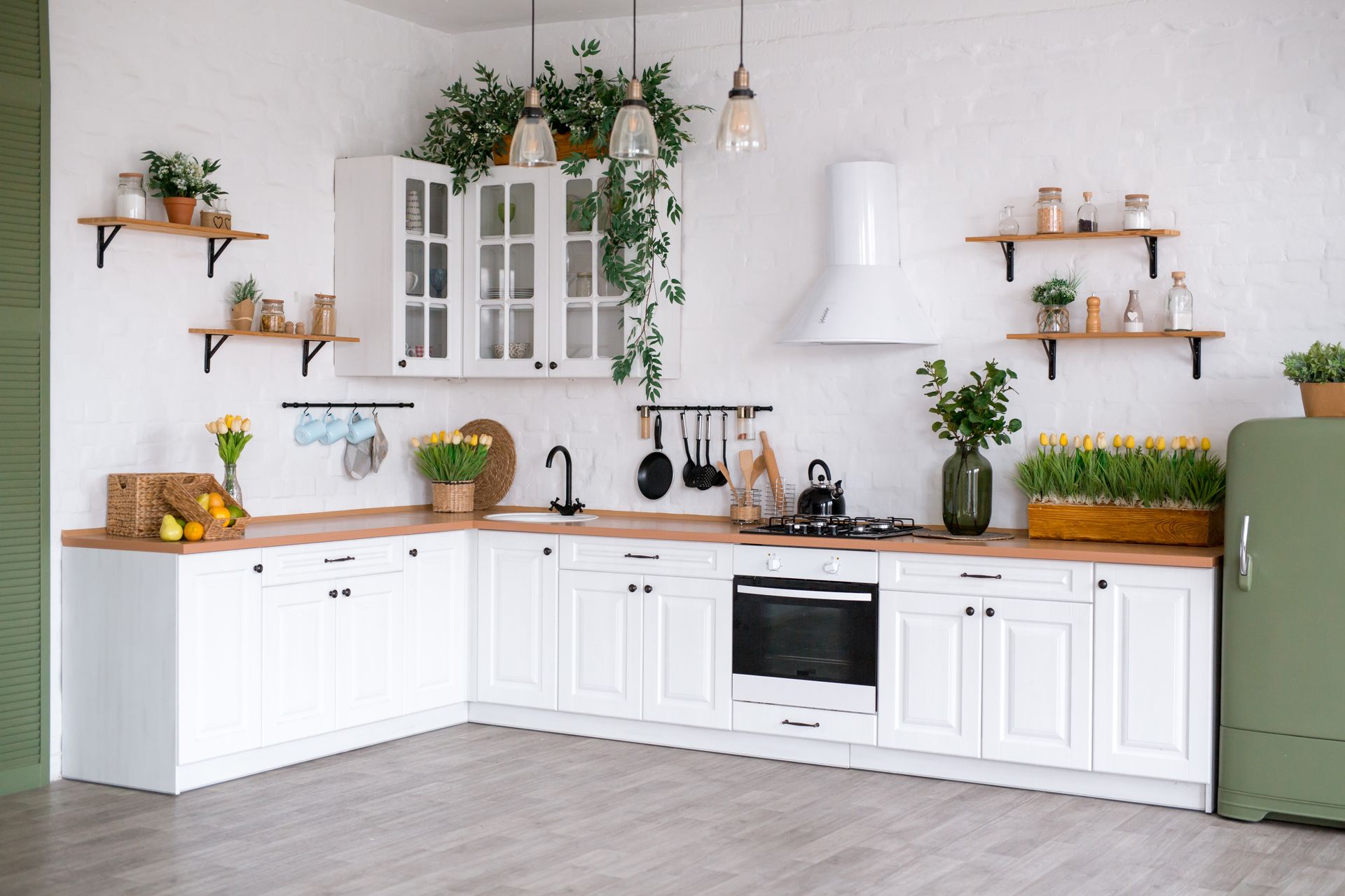 Bright white kitchen with wooden countertops, potted plants, shelves, cabinets, and a large island